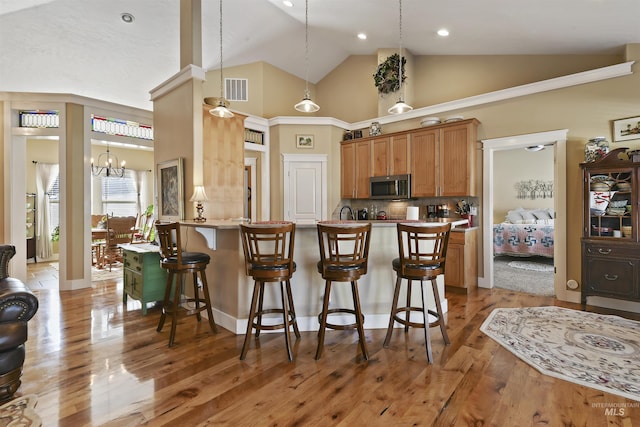 kitchen featuring light wood-type flooring, a kitchen bar, stainless steel microwave, and backsplash