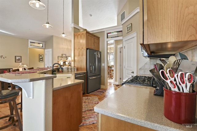 kitchen with stainless steel refrigerator with ice dispenser, a breakfast bar area, brown cabinetry, a sink, and a peninsula