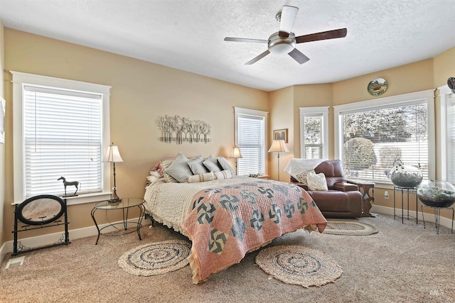 carpeted bedroom with a textured ceiling, ceiling fan, and baseboards