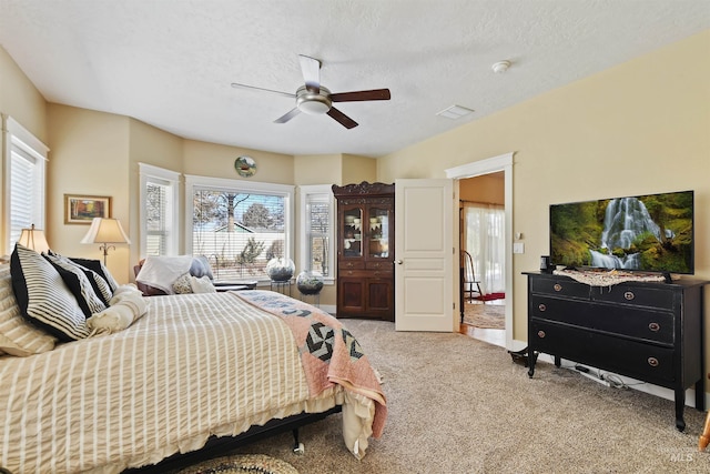 bedroom featuring light carpet, ceiling fan, multiple windows, and a textured ceiling