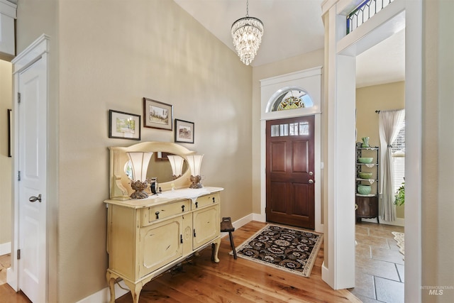 entrance foyer featuring plenty of natural light, wood finished floors, an inviting chandelier, and baseboards