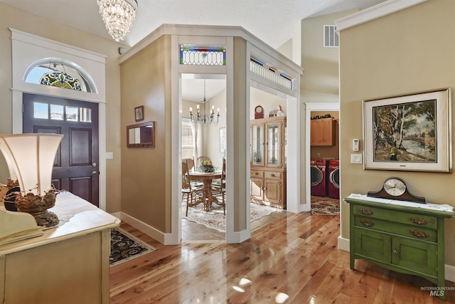 entryway featuring a chandelier, visible vents, washer and clothes dryer, and light wood finished floors