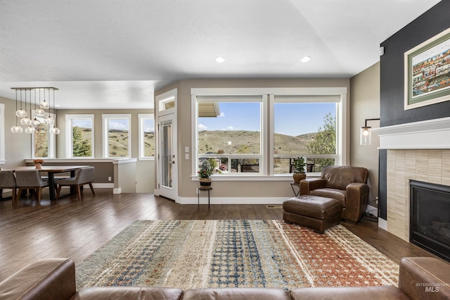 living room featuring wood-type flooring, baseboards, a tile fireplace, and recessed lighting