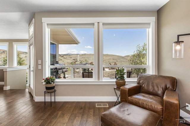 living area featuring dark wood-type flooring, visible vents, and a wealth of natural light