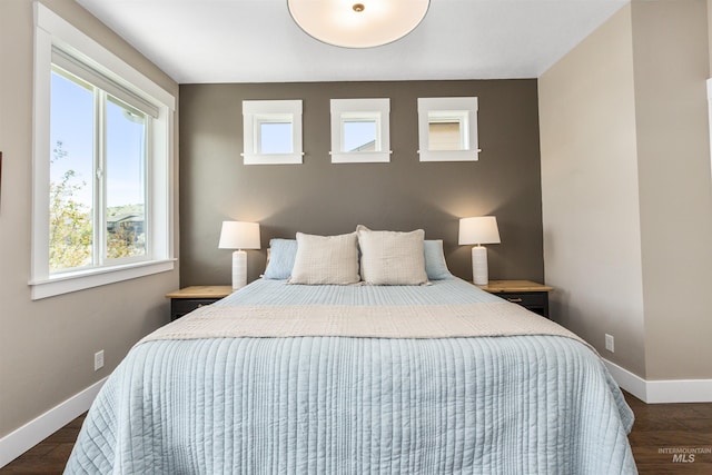 bedroom with baseboards, wood finished floors, and multiple windows