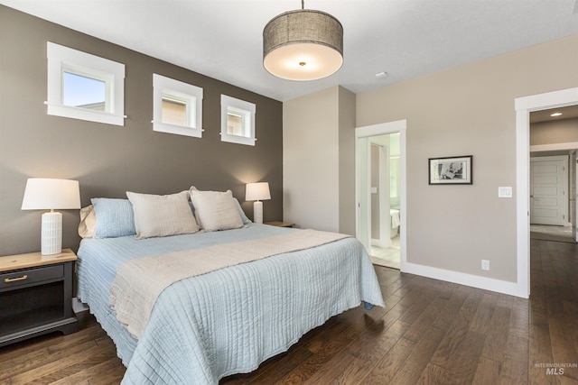 bedroom featuring ensuite bath, baseboards, and dark wood-type flooring