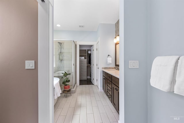bathroom featuring a spacious closet, a freestanding tub, vanity, and a stall shower