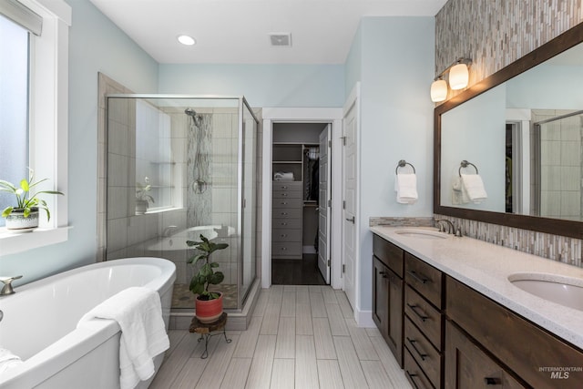 full bath featuring a soaking tub, a sink, a shower stall, and a walk in closet
