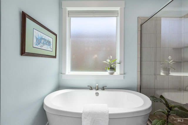 full bathroom featuring a tile shower, a wealth of natural light, and a soaking tub