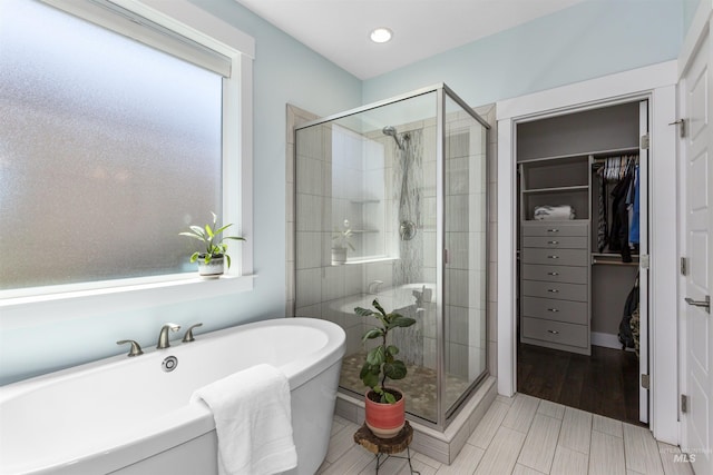 bathroom featuring a walk in closet, a healthy amount of sunlight, and a stall shower