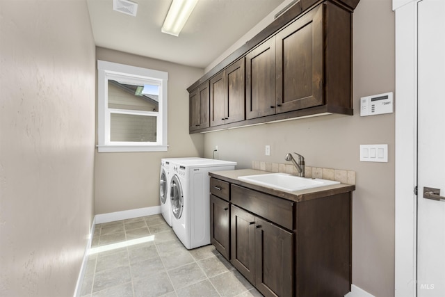 laundry area with washing machine and clothes dryer, a sink, cabinet space, baseboards, and visible vents