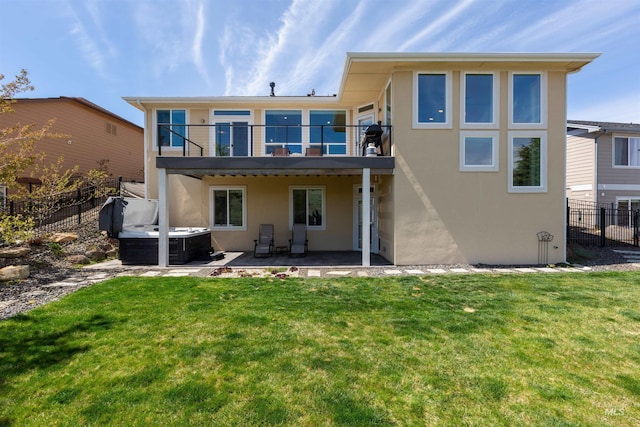 rear view of property featuring fence, a balcony, stucco siding, a patio area, and a hot tub