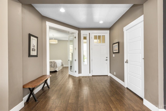foyer entrance featuring baseboards, dark wood-type flooring, visible vents, and recessed lighting