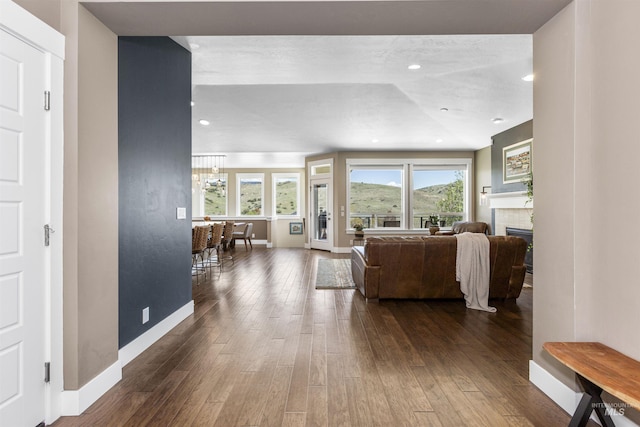 living area featuring a brick fireplace, baseboards, and dark wood-style flooring