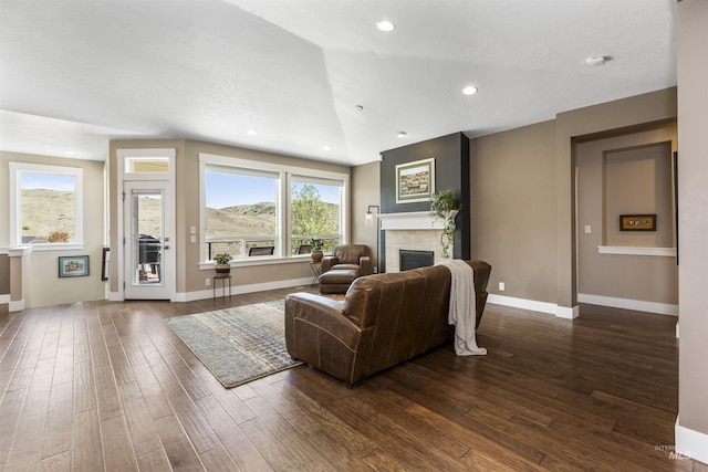 living room featuring recessed lighting, baseboards, dark wood-style floors, and a fireplace