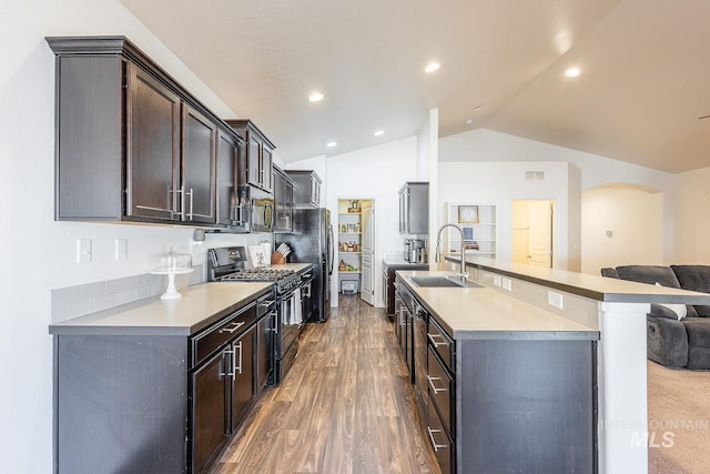 kitchen with sink, vaulted ceiling, dark brown cabinets, dark hardwood / wood-style flooring, and black appliances