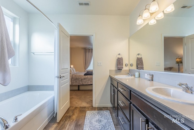 bathroom featuring hardwood / wood-style flooring, vanity, tasteful backsplash, and a bathtub