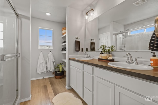 bathroom featuring hardwood / wood-style flooring, vanity, and a shower with door