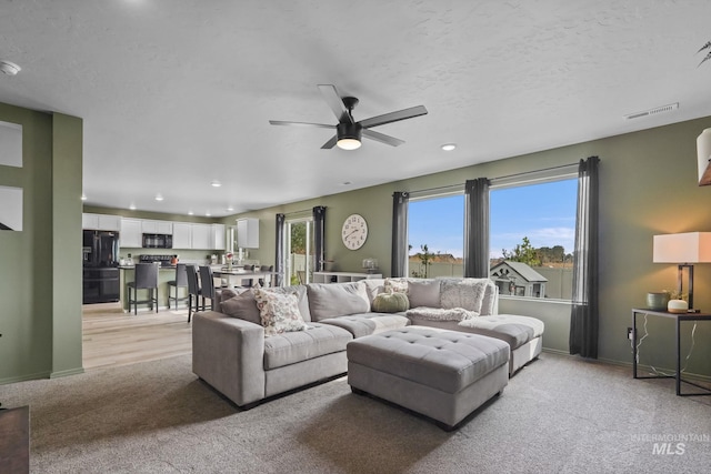 carpeted living room with ceiling fan and a textured ceiling