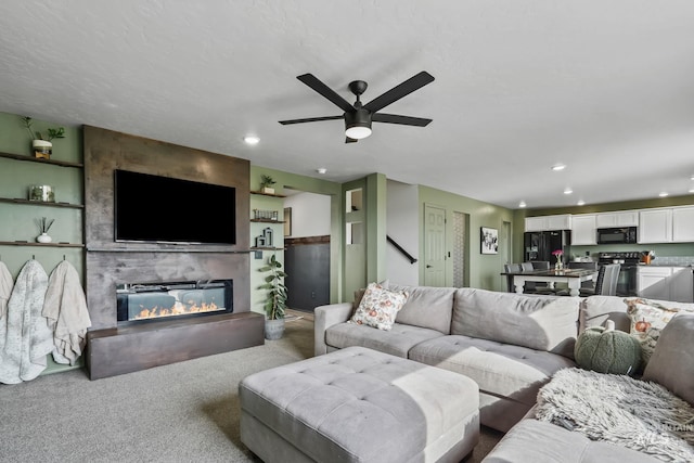 carpeted living room with ceiling fan and a fireplace