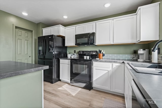 kitchen featuring sink, light hardwood / wood-style flooring, black appliances, and white cabinets