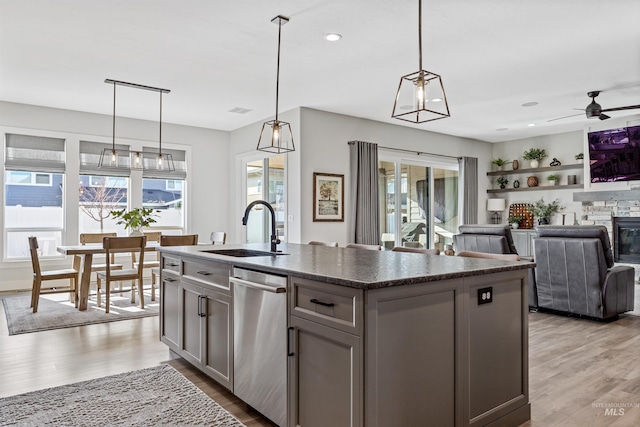 kitchen featuring decorative light fixtures, sink, gray cabinetry, and a kitchen island with sink