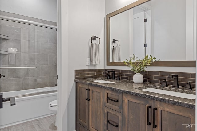 full bathroom with tasteful backsplash, toilet, shower / bath combination with glass door, and vanity