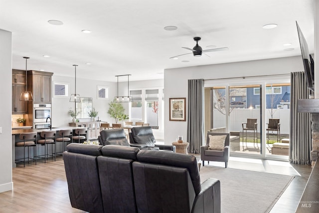 living room featuring ceiling fan, light hardwood / wood-style floors, and a wealth of natural light