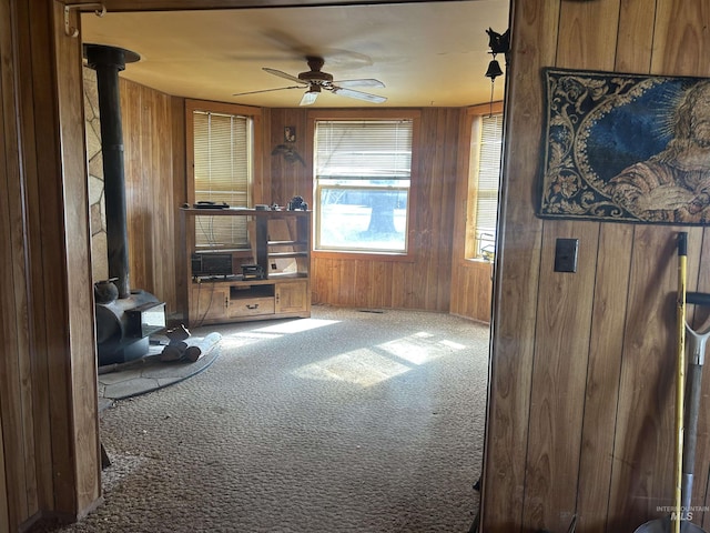 20495 Main St, Carey, ID 83320 - carpeted living area with a wood stove, ceiling fan, and wooden walls