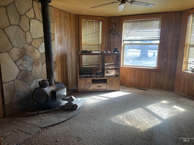 20495 Main St, Carey, ID 83320 - living room featuring wooden walls, ceiling fan, a wood stove, and carpet floors