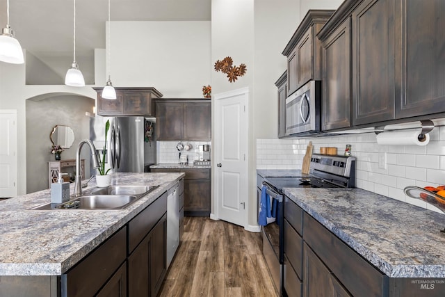 847 Bridget St, Twin Falls, ID 83301 - kitchen with appliances with stainless steel finishes, a sink, dark brown cabinetry, dark wood finished floors, and backsplash