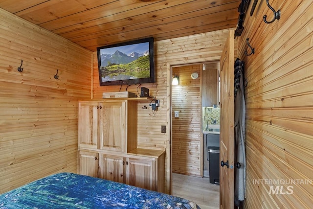 bedroom with wooden walls, wooden ceiling, and light wood-style flooring