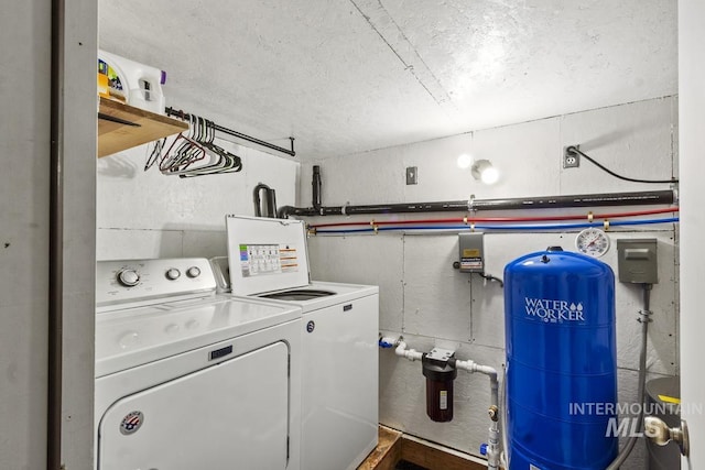 washroom featuring separate washer and dryer, laundry area, and a textured ceiling