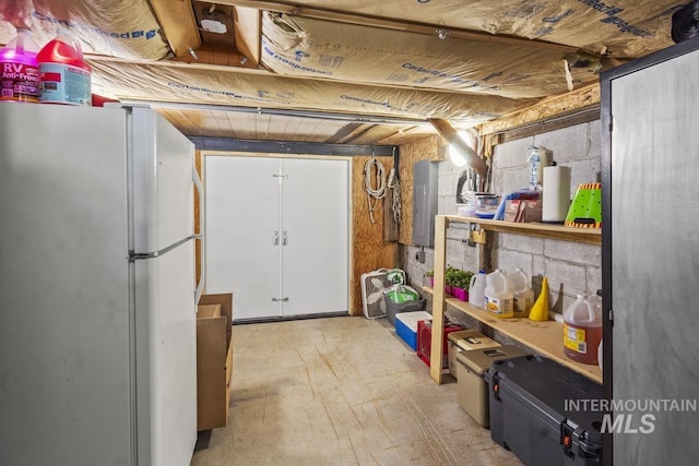 unfinished basement featuring freestanding refrigerator and electric panel