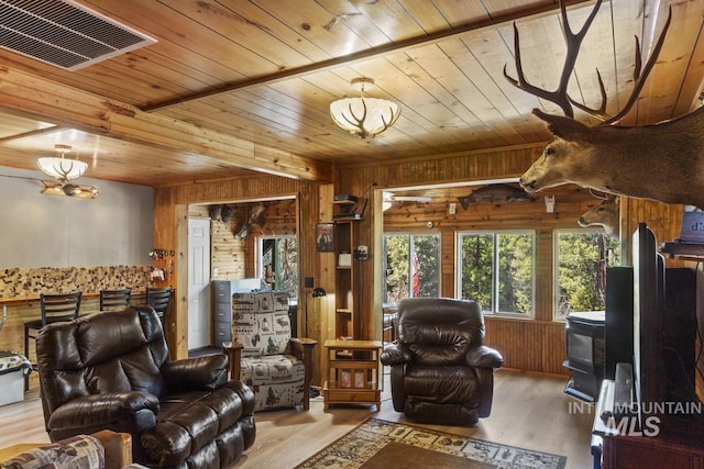 living room featuring wood walls, visible vents, wooden ceiling, and wood finished floors