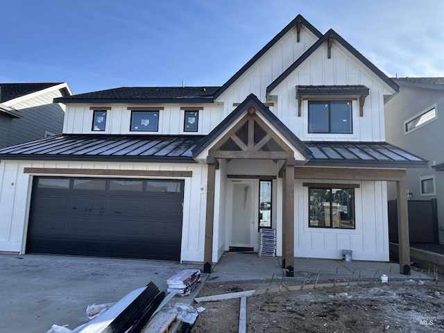 modern farmhouse style home featuring a garage, driveway, metal roof, a standing seam roof, and board and batten siding