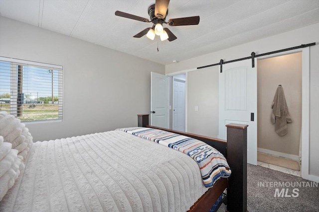 bedroom with carpet floors, a ceiling fan, and a barn door
