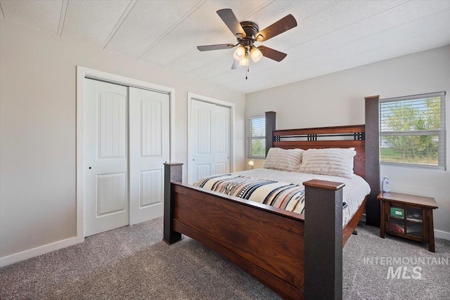 carpeted bedroom with baseboards, ceiling fan, and two closets