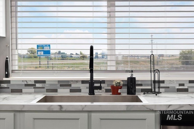 interior details with white cabinetry, a sink, and tasteful backsplash