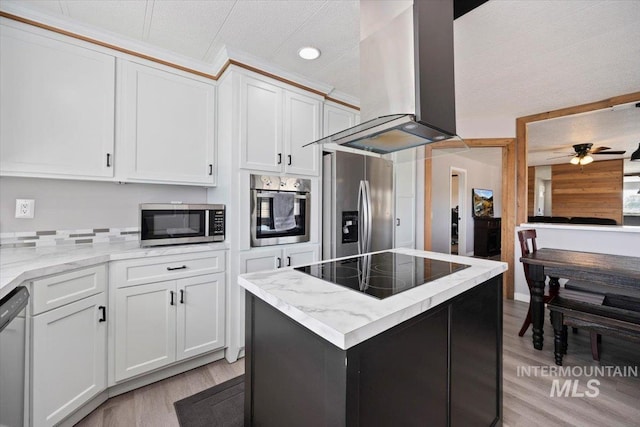 kitchen featuring wall chimney range hood, ceiling fan, light stone countertops, stainless steel appliances, and light wood-type flooring
