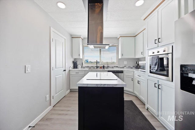 kitchen with a kitchen island, light countertops, white cabinetry, island exhaust hood, and appliances with stainless steel finishes