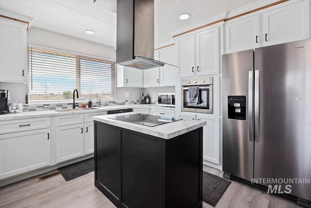 kitchen featuring wall chimney range hood, a sink, white cabinets, black appliances, and light wood-style floors