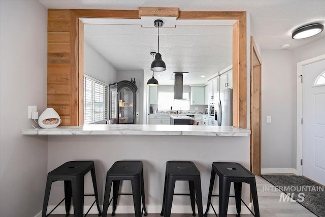 kitchen with a peninsula, stainless steel fridge, a kitchen breakfast bar, and plenty of natural light