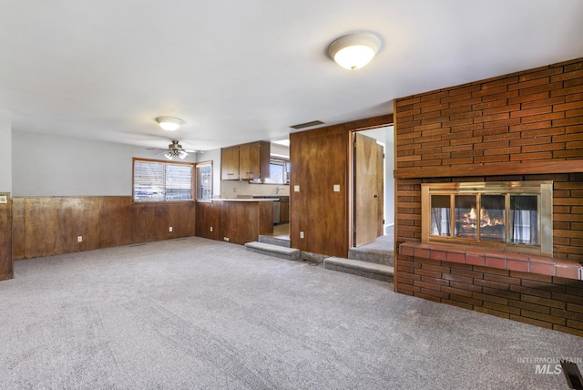 620 Monte Vista Dr, Twin Falls, ID 83301 - unfurnished living room featuring wood walls, ceiling fan, carpet flooring, and a brick fireplace