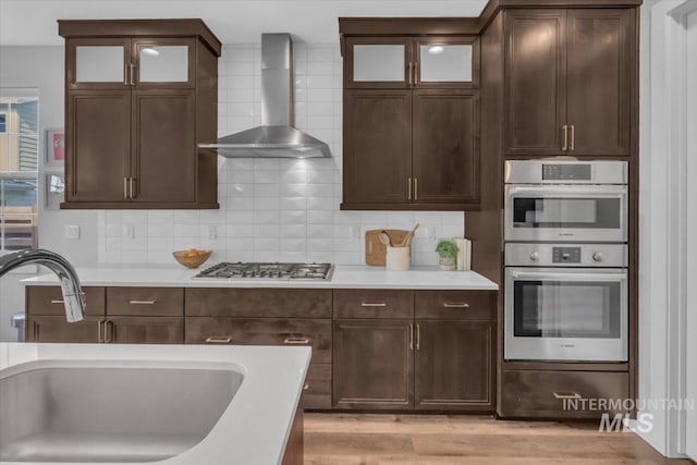 2959 S Shady Ln, Boise, ID 83716 - kitchen with wall chimney exhaust hood, a sink, stainless steel double oven, light countertops, and tasteful backsplash
