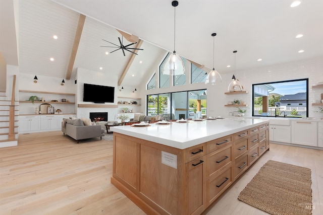 11950 W Lanktree Gulch Rd, Star, ID 83669 - kitchen featuring open shelves, a fireplace, light wood-type flooring, beam ceiling, and a spacious island