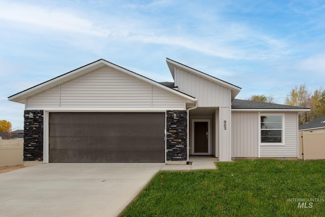 view of front facade with concrete driveway, an attached garage, fence, stone siding, and a front lawn