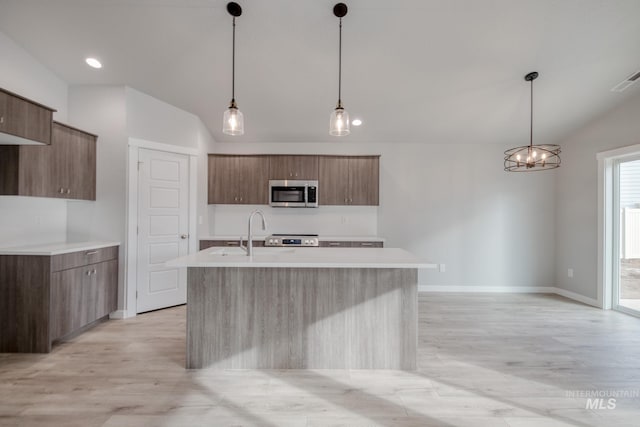 kitchen with stainless steel appliances, light countertops, vaulted ceiling, a sink, and modern cabinets