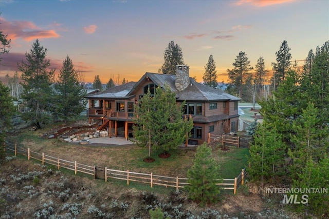 212 Ferguson Way, Mccall, ID 83638 - back of property at dusk with a deck, a patio area, stairs, and a chimney