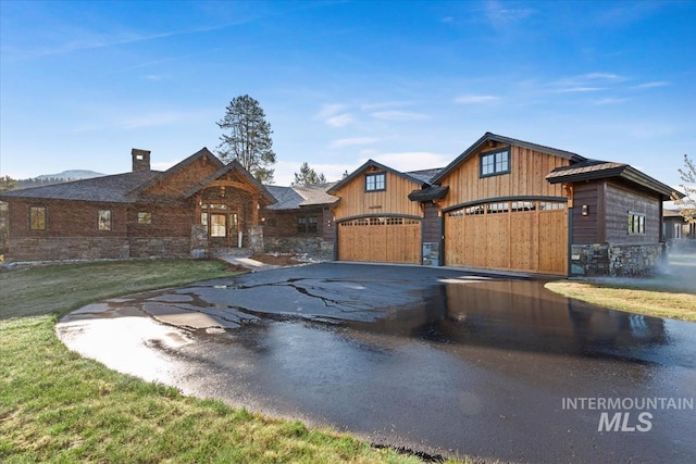 212 Ferguson Way, Mccall, ID 83638 - view of front of house featuring stone siding, asphalt driveway, a garage, a chimney, and a front lawn
